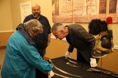 People looking at artifacts on a table in Alamo Hall