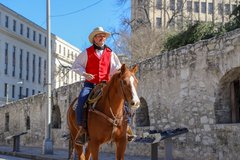 Man in a red vest riding a horse by the Long Barrack
