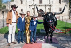 Couple with two boys next to a longhorn in front of Alamo Church