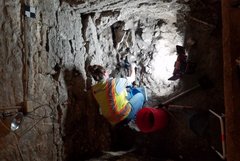 Archaeologist inspecting stones inside an excavation unit