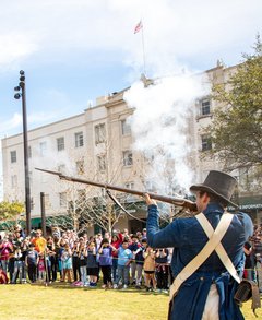 Living historians firing a musket in front of a large crowd in Plaza de Valero