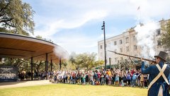 Living historians firing a musket in front of a large crowd in Plaza de Valero