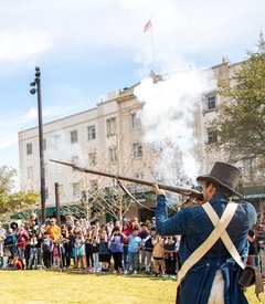 Living historians firing a musket in front of a large crowd in Plaza de Valero