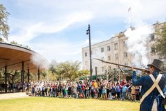 Living historians firing a musket in front of a large crowd in Plaza de Valero