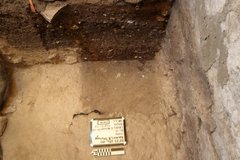 Inside corner of an excavation unit with a white board and ruler at the bottom