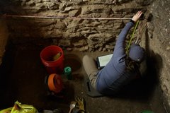 Archaeologist measuring length of limestone inside an excavation unit
