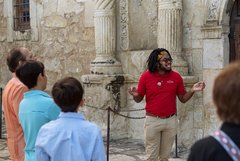 Tour guide with a group of visitors outside of Alamo Church