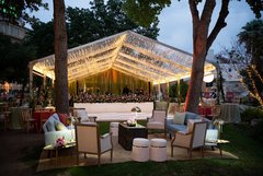 Dance floor and lighted outdoor tent with blue and cream lounge furniture at the end of the tent