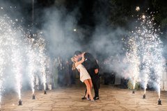 Bride and groom kissing in between two rows of cold sparklers