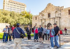 Group of people listening to a tour guide in front of Alamo Church