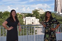 Two women at La Vista Terrace with the Alamo in the background