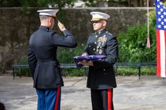 Marine saluting a General holding a folded American flag