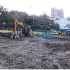Construction trucks paving area in excavation plot