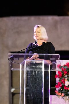 Commissioner Dawn Buckingham in a black dress in front of a podium on stage at an event