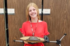 Young woman with red shirt and blue jeans holding a palm leaf hat with a leather crown