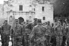 Sergeant Sawyer saluting with the Alamo Church in the background surrounded by soldiers