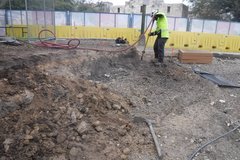 Construction worker air-spading the above-surface planter walls