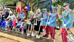 Children and adults holding shovels to dig in a dirt box during a ceremony