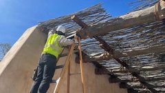 Construction worker on a ladder adding a shade layer over the Mission Gate
