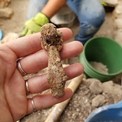 Hand holding an artifact that appears to be a door latch