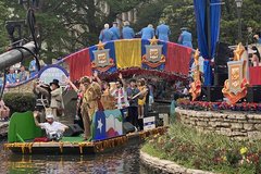 Commissioner Buckingham waving at the audience on a river parade float with a decorative large Alamo sculpture