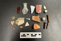 Glass and ceramic artifact fragments next to a ruler for size