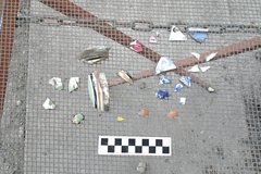 Ceramic fragments on a wire screen next to a ruler for size