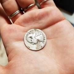 A worn US quarter dated 1937 in the palm of a hand