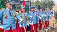 Men in blue jackets and red pants holding shovels at a groundbreaking ceremony