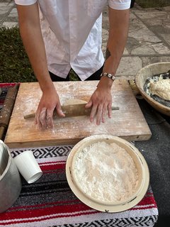 Man rolling tortillas with a rolling pin on a cutting board covered in flour