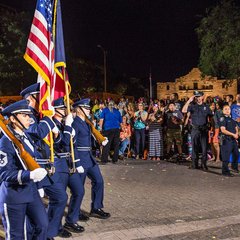 Four Air Force servicemen marching in front of the Alamo during a night parade
