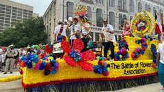 Festive parade float with yellow trim and florals passing through