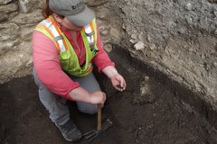 Archaeologist examining dirt in her hand inside an excavation unit