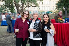 Three ladies smiling in Alamo Gardens near a cocktail table with a red linen