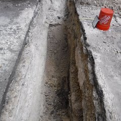 Excavation area with orange Home Depot bucket and yellow tape measure