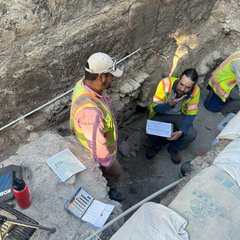 Two archaeologists inside an excavation unit looking at soil profiles
