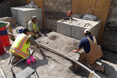 Three workers digging in an excavation area