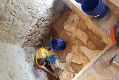 Archaeologist digging inside an excavation unit