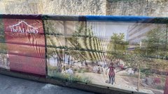 Fence wrap with red Alamo logo and rendering of future Paseo del Alamo