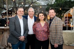 Three men and a woman smiling at an outdoor event