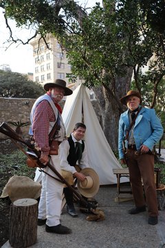 Two standing and one seated living historian next to a tent