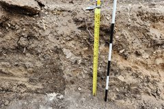 Yellow tape measure indicating height of excavation unit