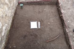 White board and marker at center of dirt surface inside an excavation unit