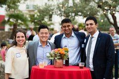 Four guests smiling around a cocktail table with red linens and colorful flowers