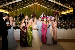 Bride and friends dressed in gowns on the dance floor under string lighting
