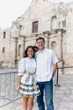Man and a woman posing in front of Alamo Church