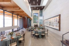 Round tables with blue linens set up in lobby next to a wall with artifacts on display