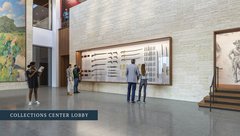 Visitors looking a display of weapons on the wall of a museum lobby