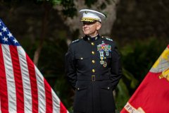 Marine General smiling in front of the American and Marine flags