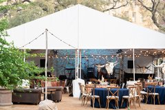 Large tented structure set up for an event with round tables inside and outside of tent